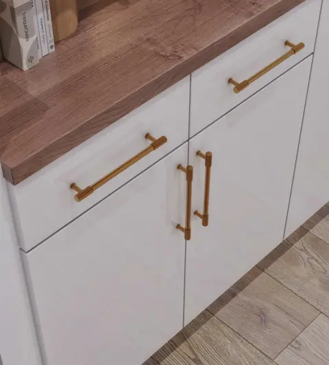 Close-up of a white vanity with a wood countertop and brass pulls