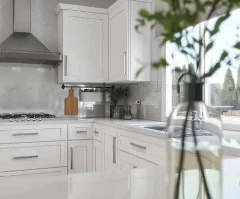 White kitchen cabinets around a corner with a stainless range hood